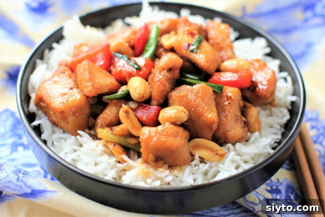 black bowl with kung pao chicken on rice, chopsticks on side