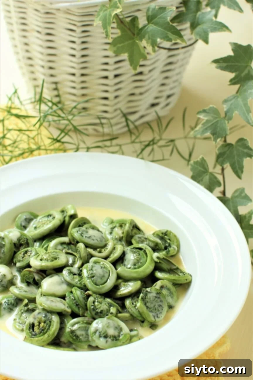 a white plate of fiddleheads swimming in Beurre Blanc