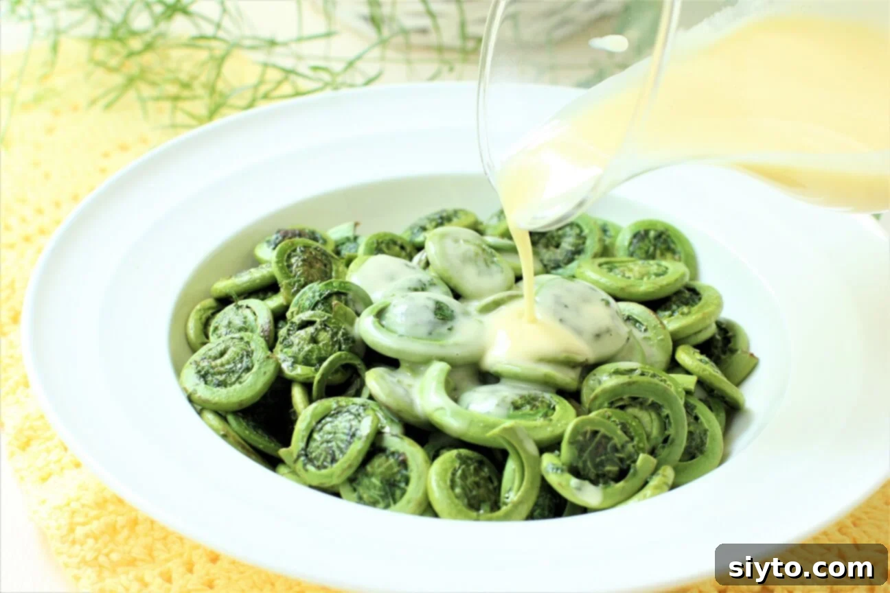 horizontal - drizzling butter sauce onto the fiddleheads