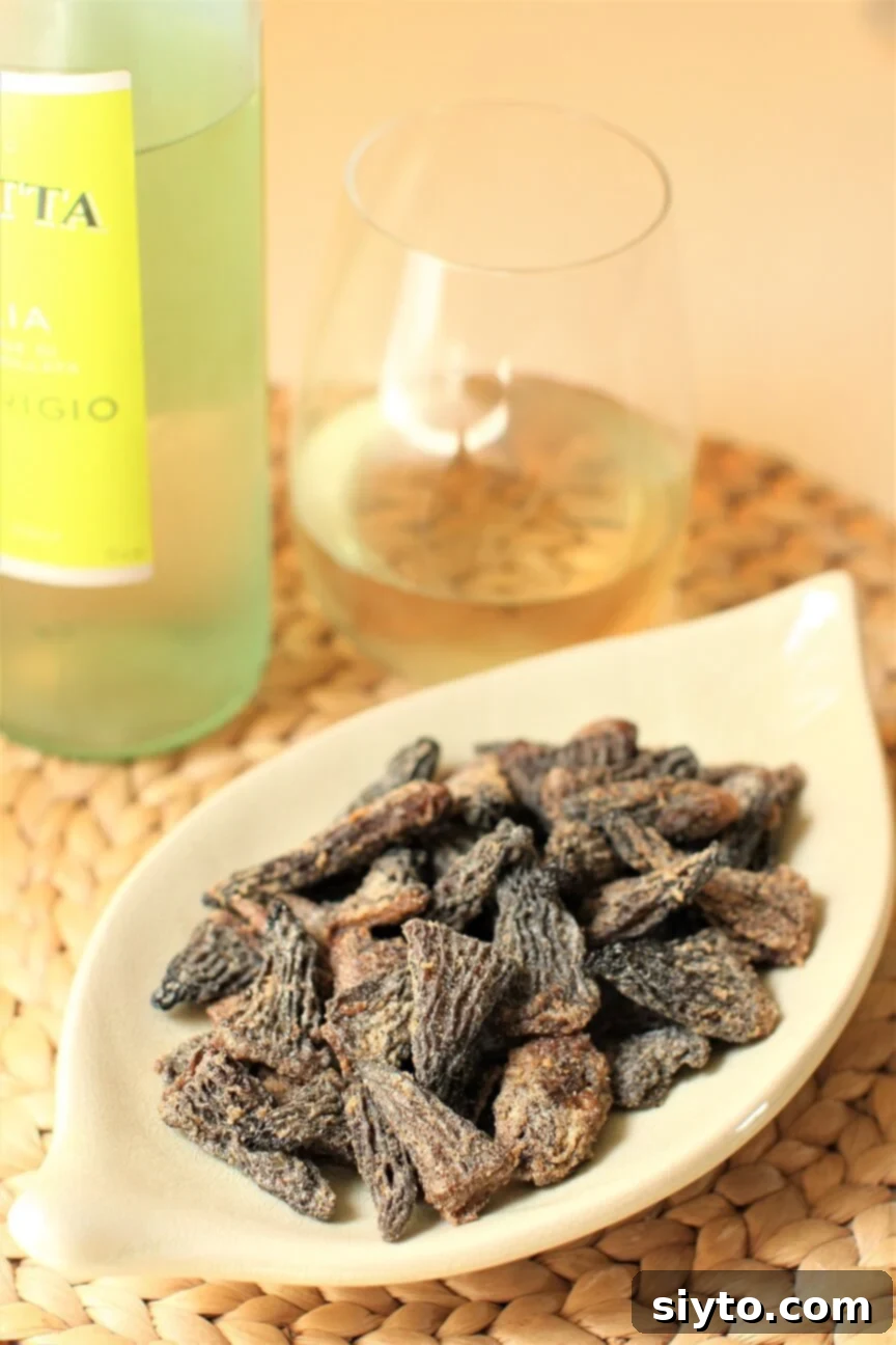 Savory Pan Fried Morel Mushroom Bites 2 A beautifully presented dish of golden-brown pan-fried morel mushrooms, accompanied by a glass of chilled white wine, inviting culinary enjoyment