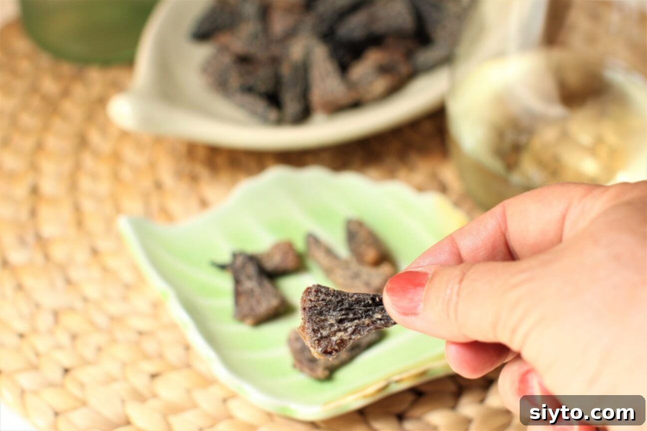 Savory Pan Fried Morel Mushroom Bites 11 A hand reaching to pick up a perfectly fried morel mushroom from a serving dish, highlighting the inviting texture and readiness to be tasted