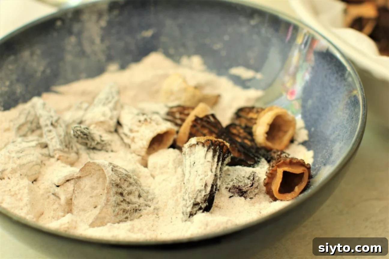Savory Pan Fried Morel Mushroom Bites 9 Fresh morel mushroom caps being gently tossed in a bowl of seasoned flour, ensuring an even and flavorful coating before frying