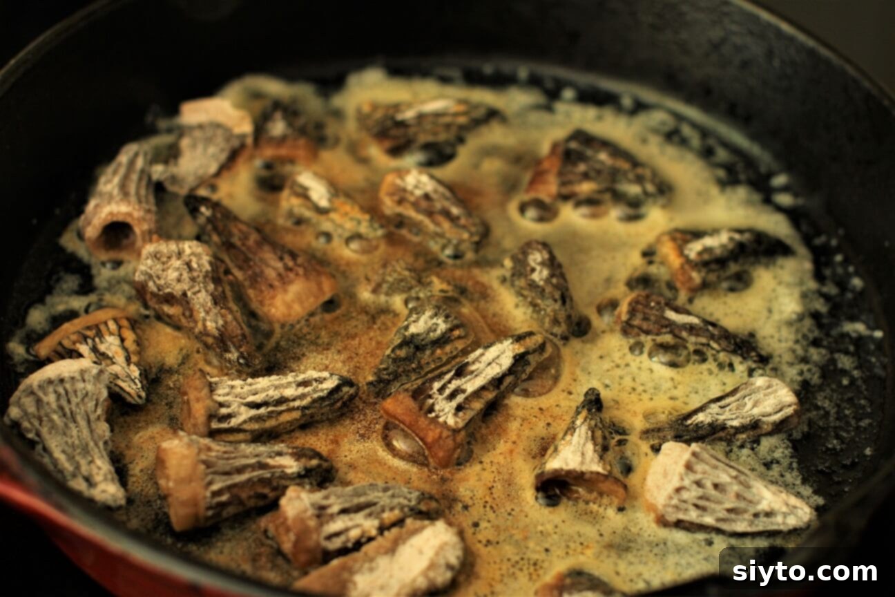 Savory Pan Fried Morel Mushroom Bites 10 Close-up of golden-brown morel mushrooms sizzling in melted butter in a hot skillet, showcasing the pan-frying process for a crispy finish