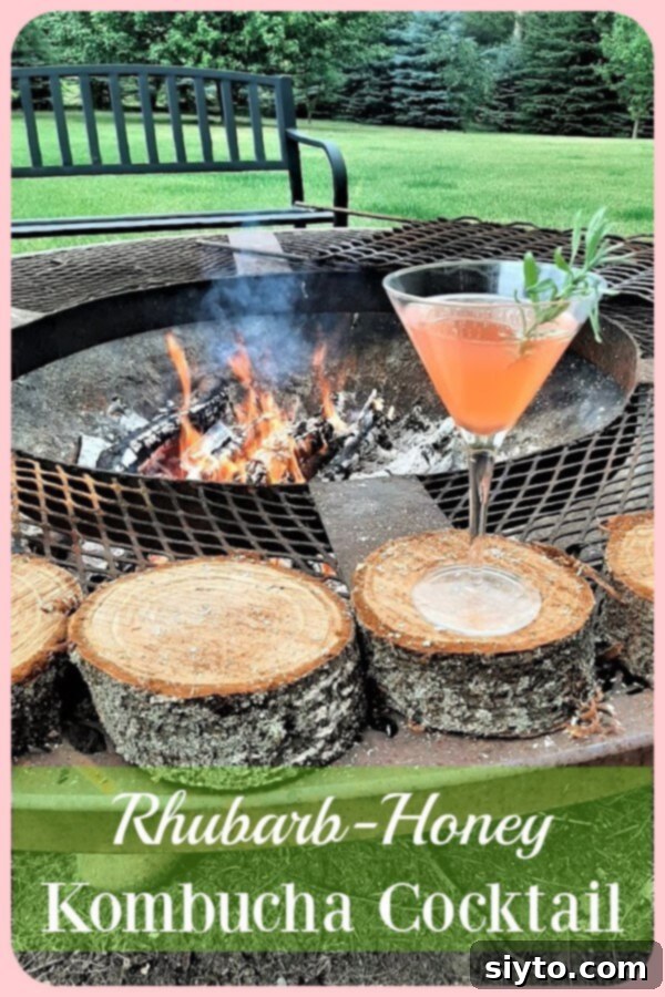 Sweet Rhuby Kombucha Cocktail with lavender sprig on a log near a glowing campfire