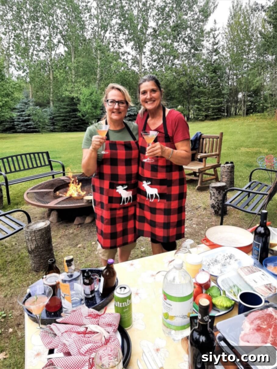 Sabina and the author in matching aprons, toasting with 'Sweet Rhuby' kombucha cocktails by the campfire