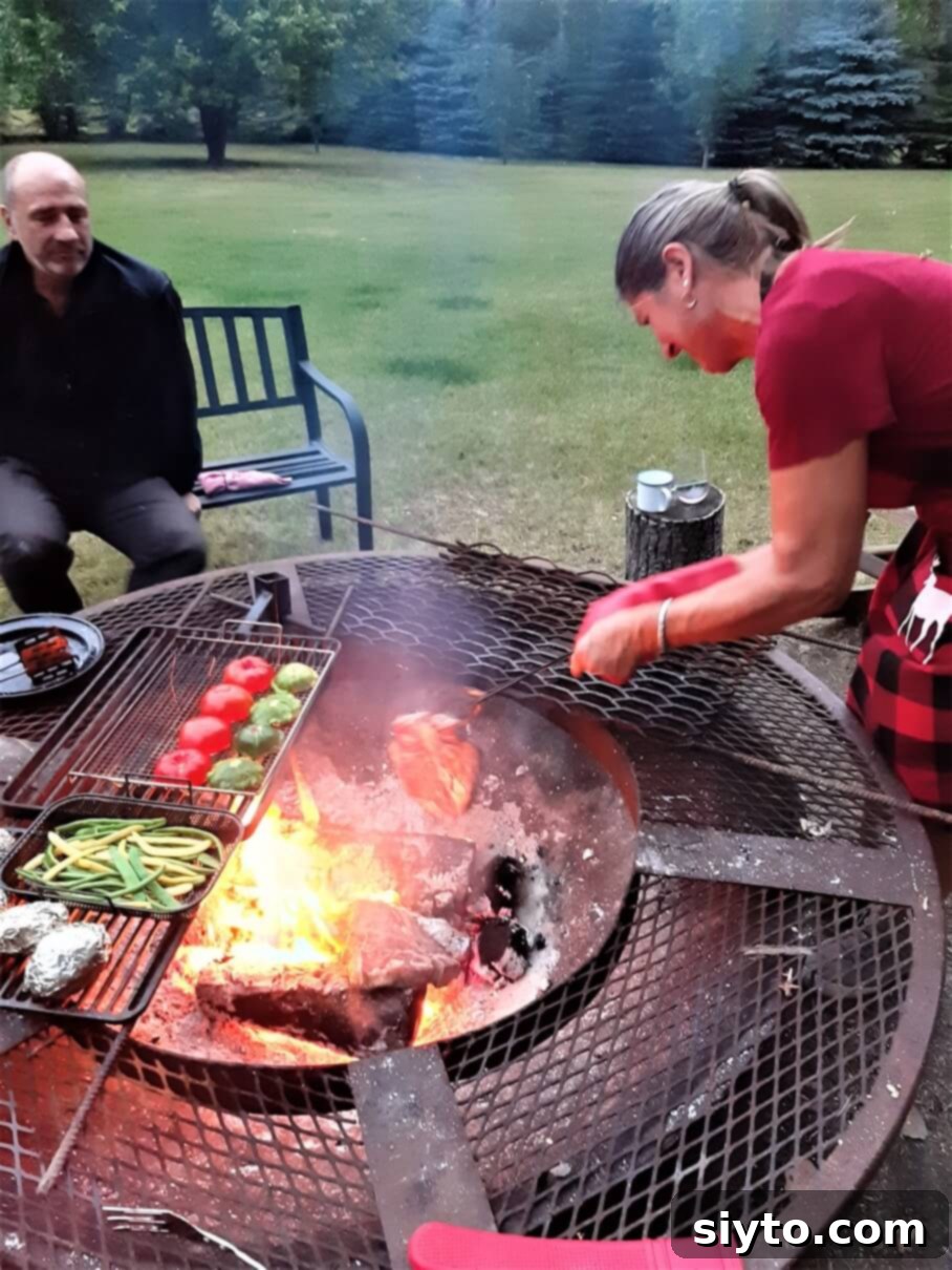 Sabina carefully turning porterhouse steaks directly on the campfire coals with tongs