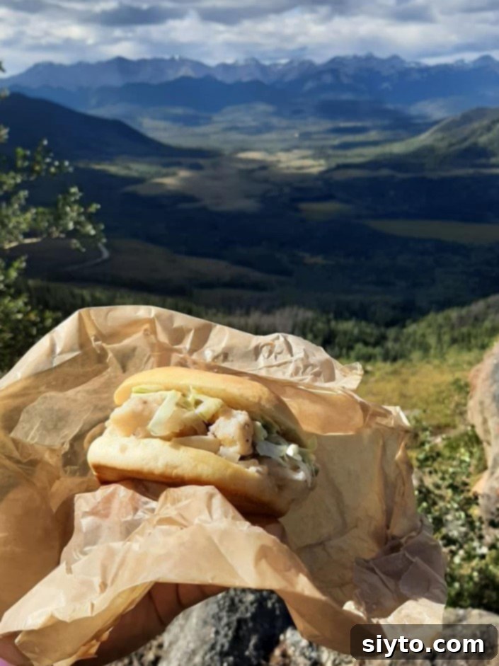A perfectly loaded bun with flaky fried tilapia and creamy coleslaw, ideal for a mountain picnic lunch.