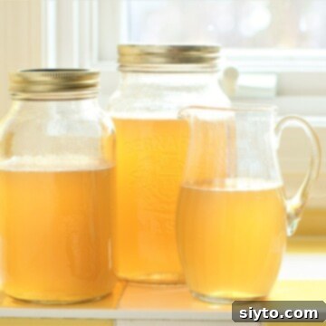 Two jars and a pitcher filled with homemade Instant Pot Chicken Stock, ready for storage.