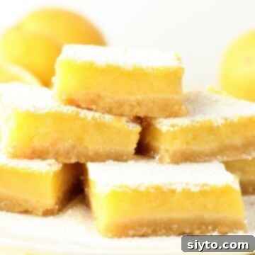 A serving plate featuring several perfectly cut gluten-free lemon bars, lightly dusted with powdered sugar.