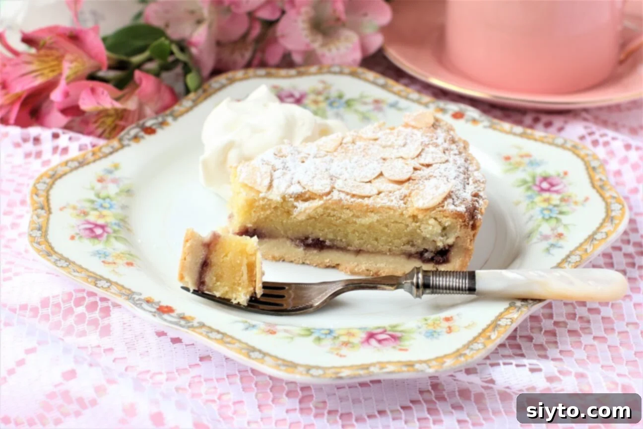 Traditional Bakewell Tart 2 A close-up of a forkful of Bakewell Tart, showing the distinct layers of buttery shortcrust pastry, sweet raspberry jam, and moist almond frangipane, ready to be enjoyed. A true British classic.