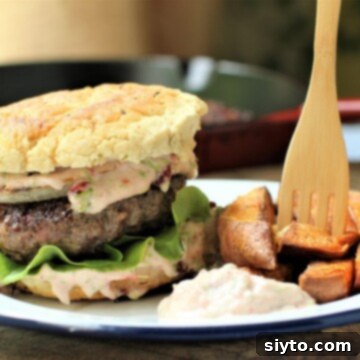 A delicious and juicy bison burger is served alongside sweet potato fries, perfect for a hearty meal