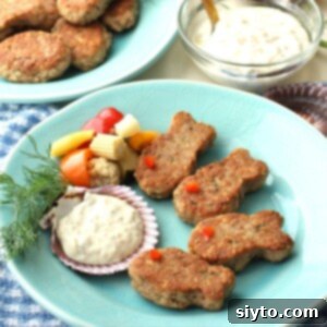 square thumbnail - blue plate with four fish-shaped tuna patties and tartar sauce in a seashell, few pickled vegetables and dill sprig