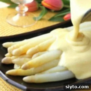 Classic White Asparagus with Effortless Hollandaise 2 Pouring a luscious puddle of easy Hollandaise sauce over a stack of perfectly cooked white asparagus spears on a chic black plate, highlighting the rich, creamy texture of the sauce.