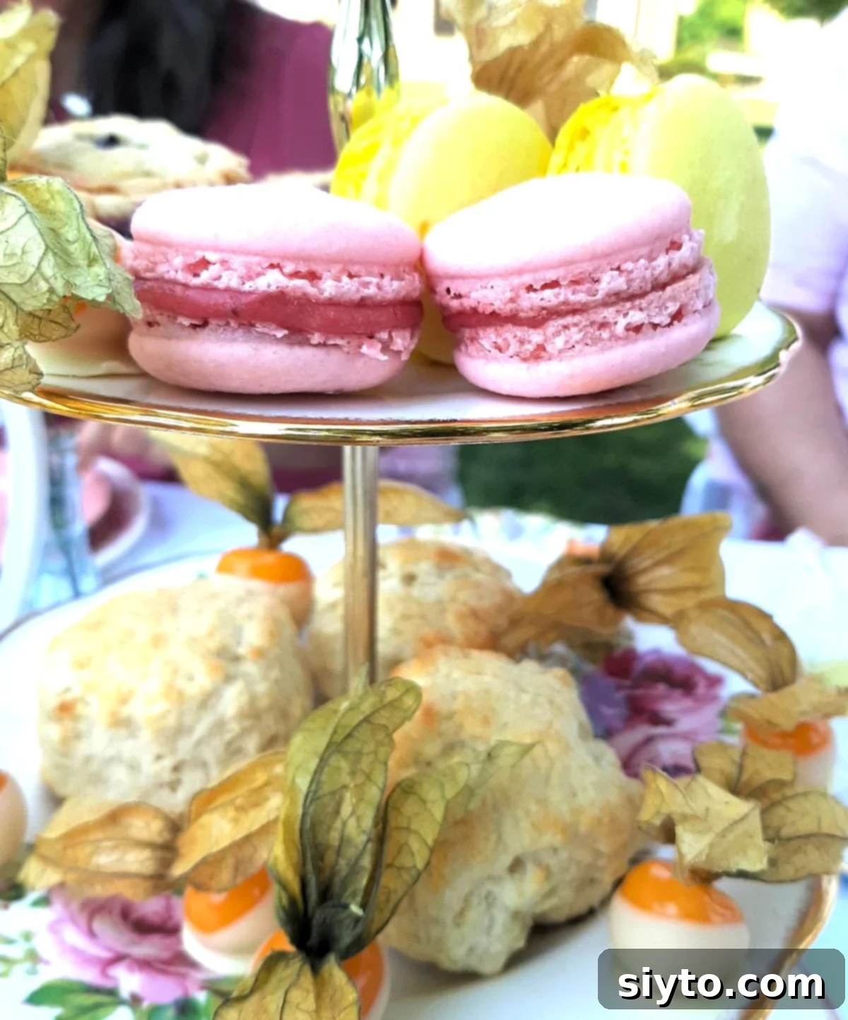 macarons on the top tier of the cake stand and scones and chocolate-dipped physalis on the middle tier.