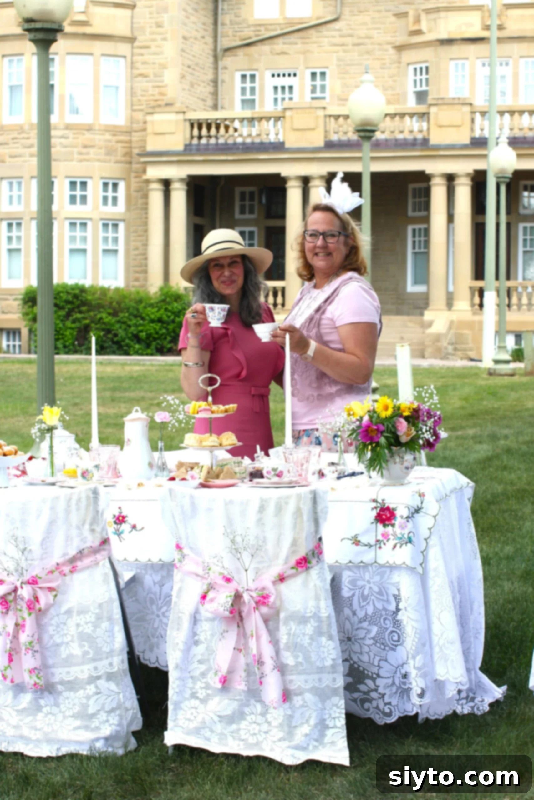Nicoletta and Margaret toasting tea cups at the tea table in front of Government House.