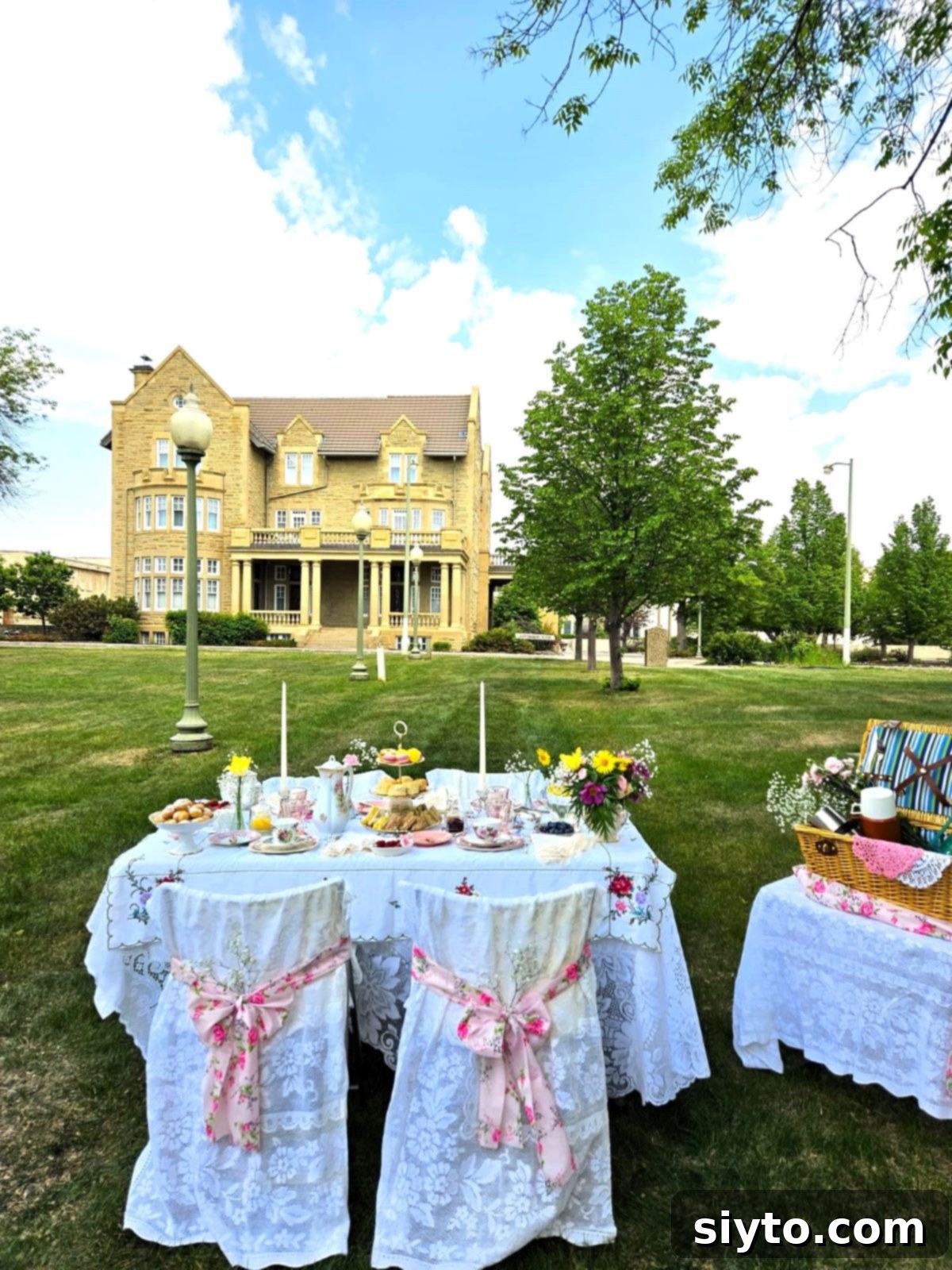 Afternoon Tea Table set with lace and china on lawn, Edmonton's Government House in the background.