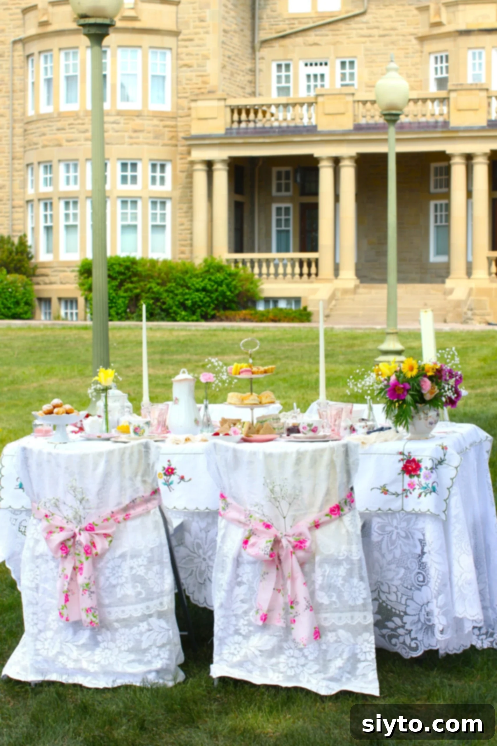 beautifully set tea table with lace-covered chairs set on the lawn in front of Government House.
