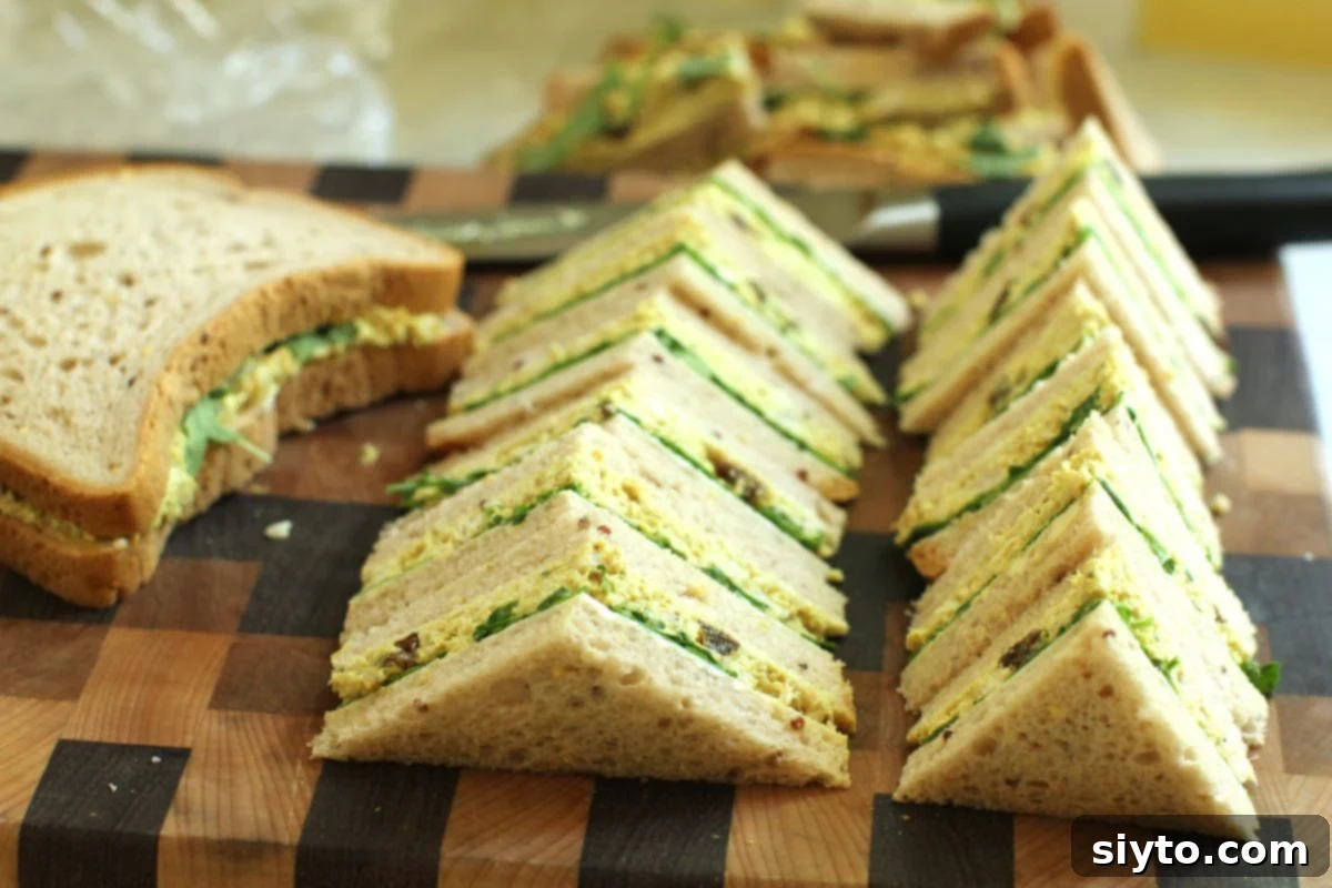 cutting board with two rows of coronation chicken salad sandwich triangles.