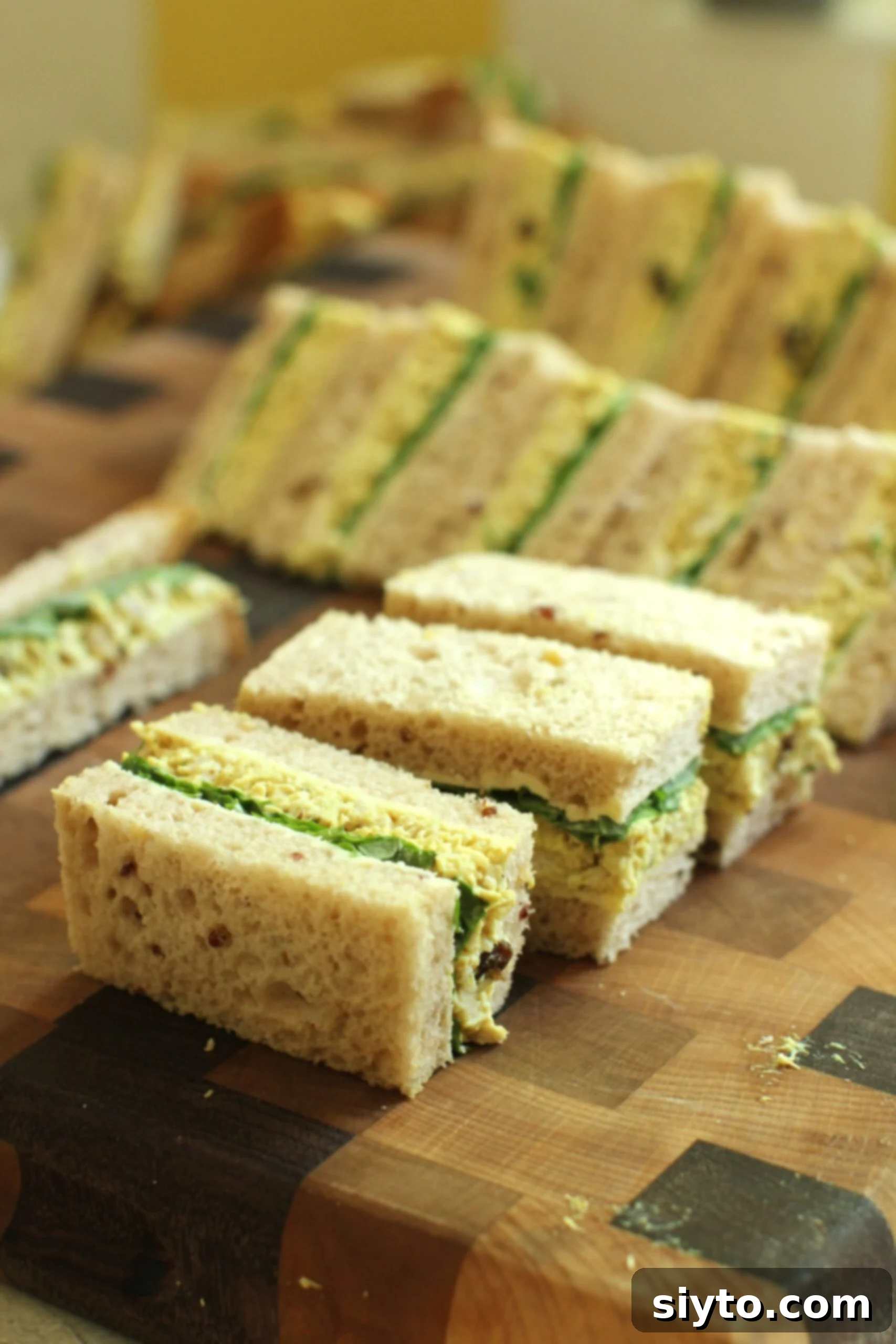 rectangular finger sandwiches of coronation chicken salad filling, on cutting board