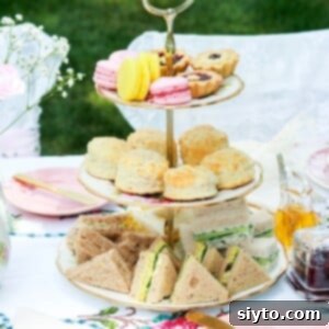 3-tier cake stand on tea table with Coronation Chicken Salad Sandwiches on bottom, scones in middle, pastries on top.