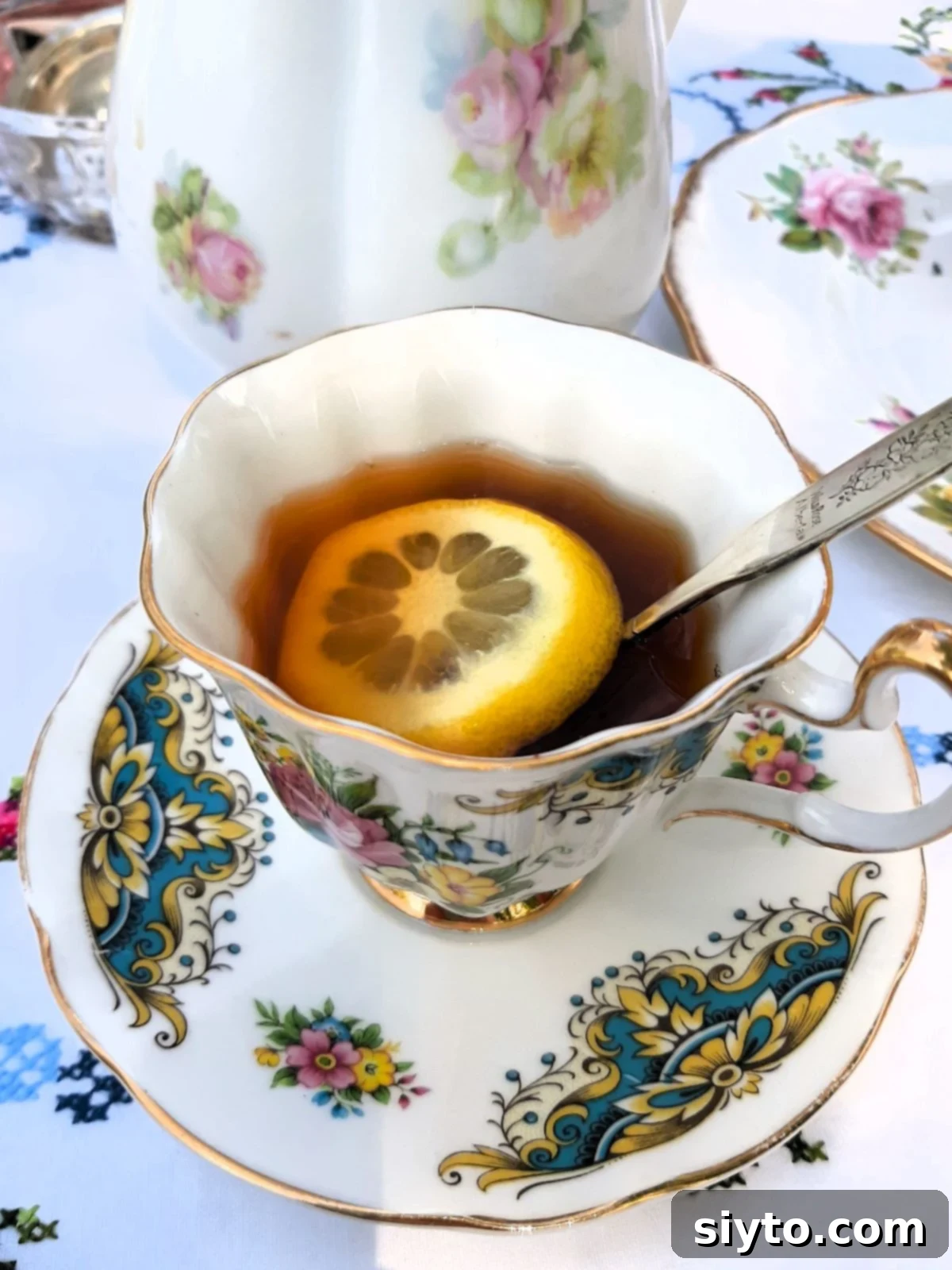 china cup with tea and a slice of lemon floating in it, with teaspoon.
