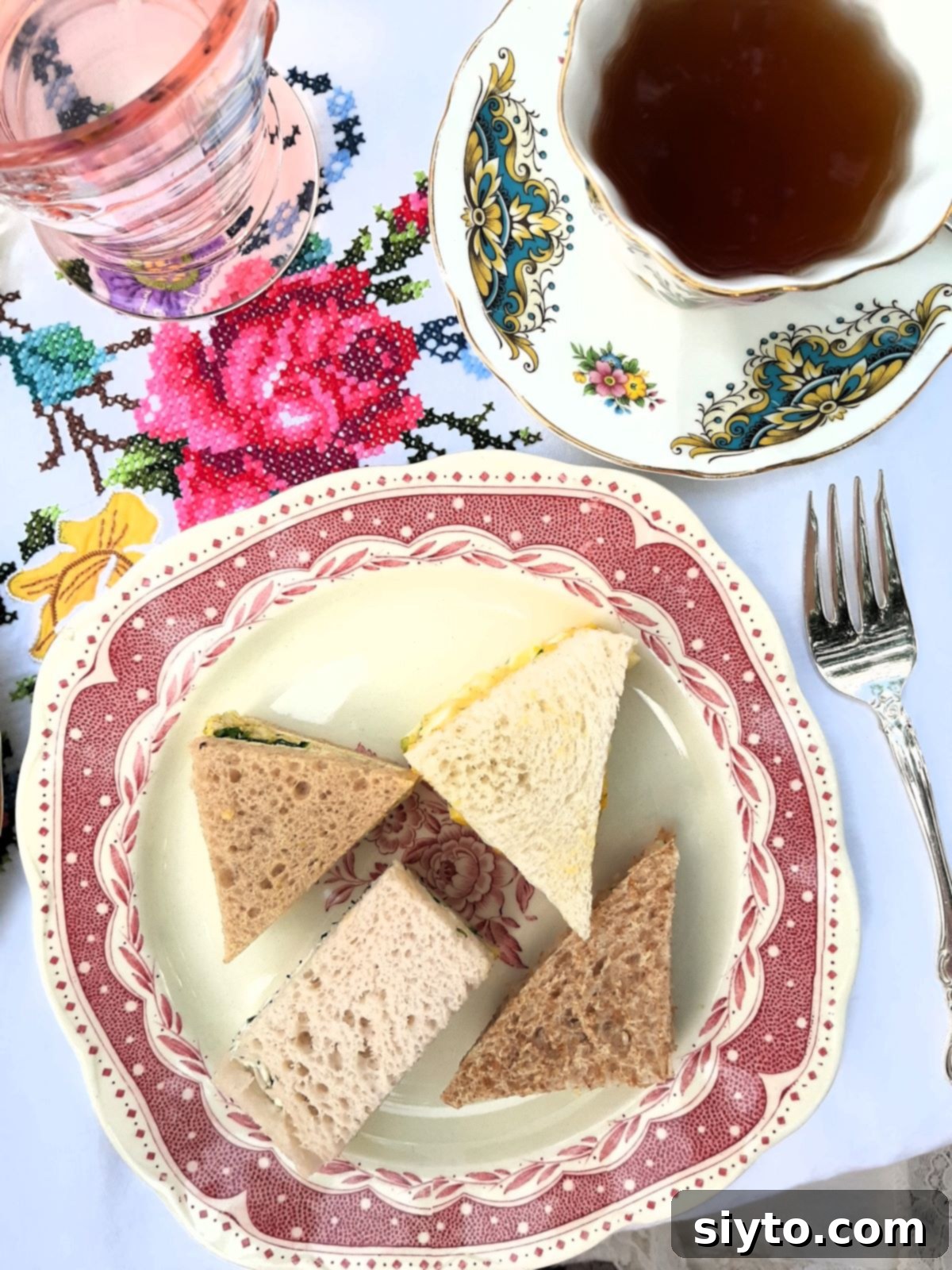 small sandwich plate with one of each type of finger sandwiches on it, cup of tea in corner.