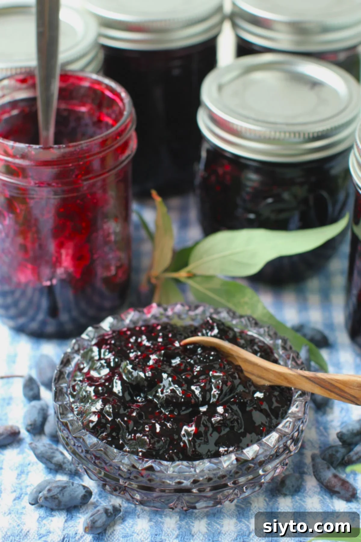 Homemade Haskap Honeyberry Jam Without Pectin 9 A elegant cut glass bowl filled with rich haskap (honeyberry) jam, positioned in front of a sealed jam jar, highlighting the jam's beautiful color and texture.