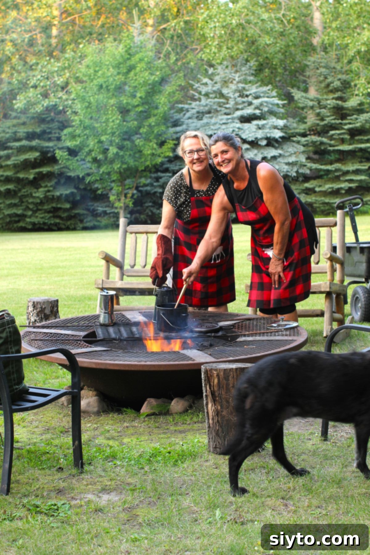 Margaret and Sabina, dressed in matching red plaid aprons, joyfully cooking together over a crackling campfire, embodying the spirit of outdoor culinary adventures.