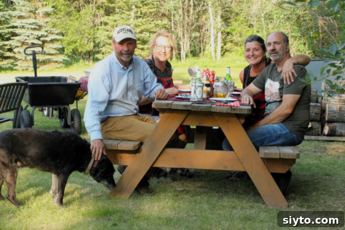 Four friends gathered around a picnic table with Pippa, the black Labrador, eagerly awaiting a delicious campfire feast.