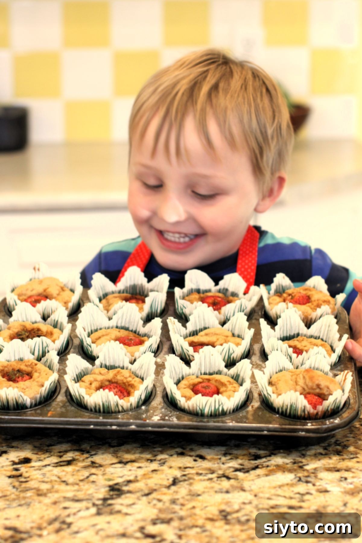Caleb looking down with pride at his tin full of Peek-a-Boo Muffins that he made himself.