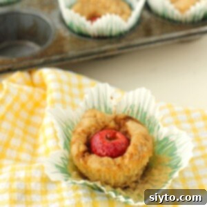 thumbnail photo of a close-up of a Peek-a-Boo muffin in its pulled-out paper liner on a yellow-checked cloth.