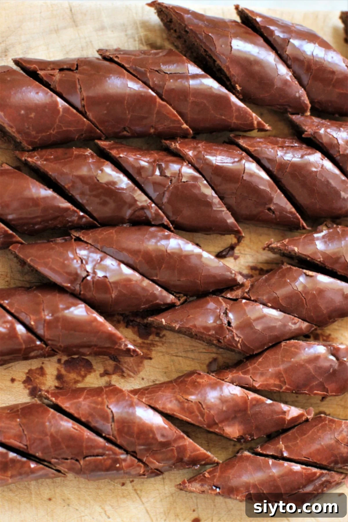 looking down at a pile of the cut and iced cookies on a wooden cutting board.