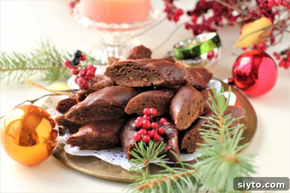a plate of cut Magenbrot with Christmas berries and evergreen sprigs around it.