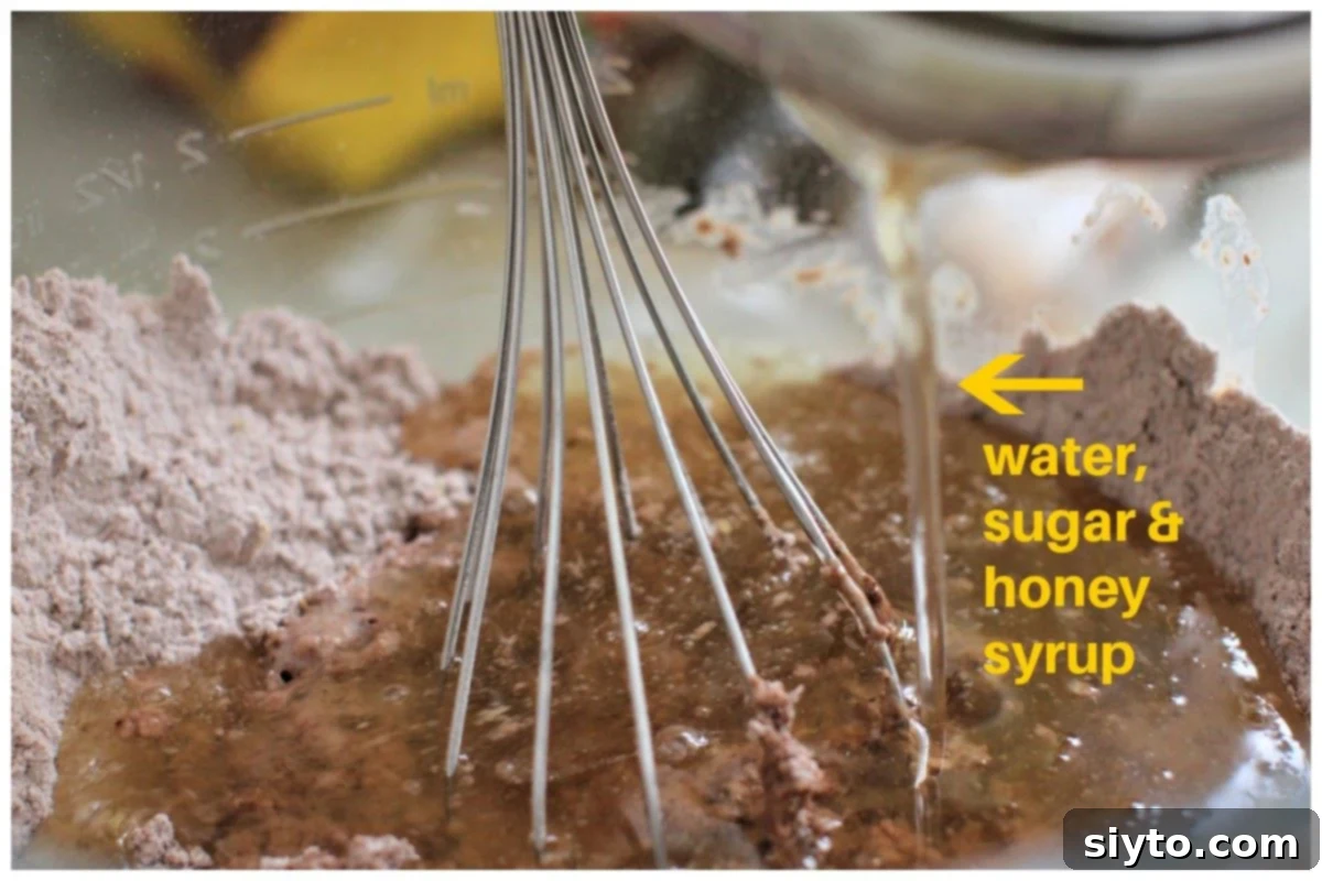 pouring the honey syrup into the dry ingredients and whisking it.