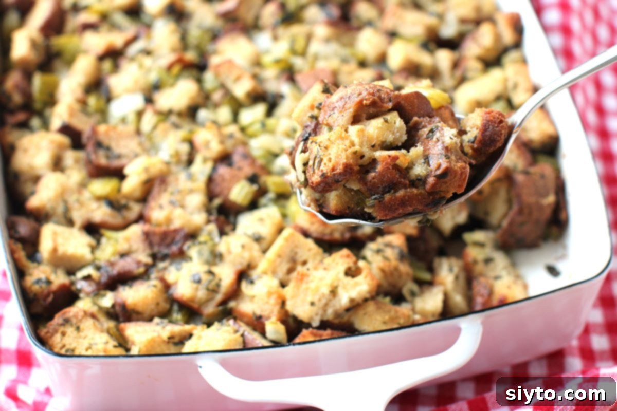 A serving spoon lifting a generous portion of fluffy, golden-brown stuffing from the pan, highlighting its appealing texture and crisp edges.