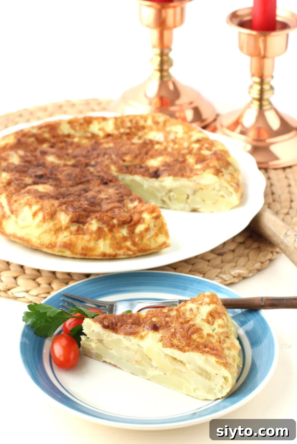 a slice of tortilla de patatas on a blue-rimmed plate, in front of the whole tortilla.