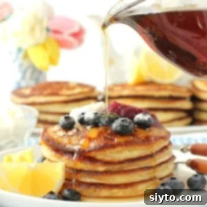 Fluffy Lemon Ricotta Pancakes 10 Lemon Ricotta Pancakes thumbnail with syrup drizzling from pitcher onto pancake stack.