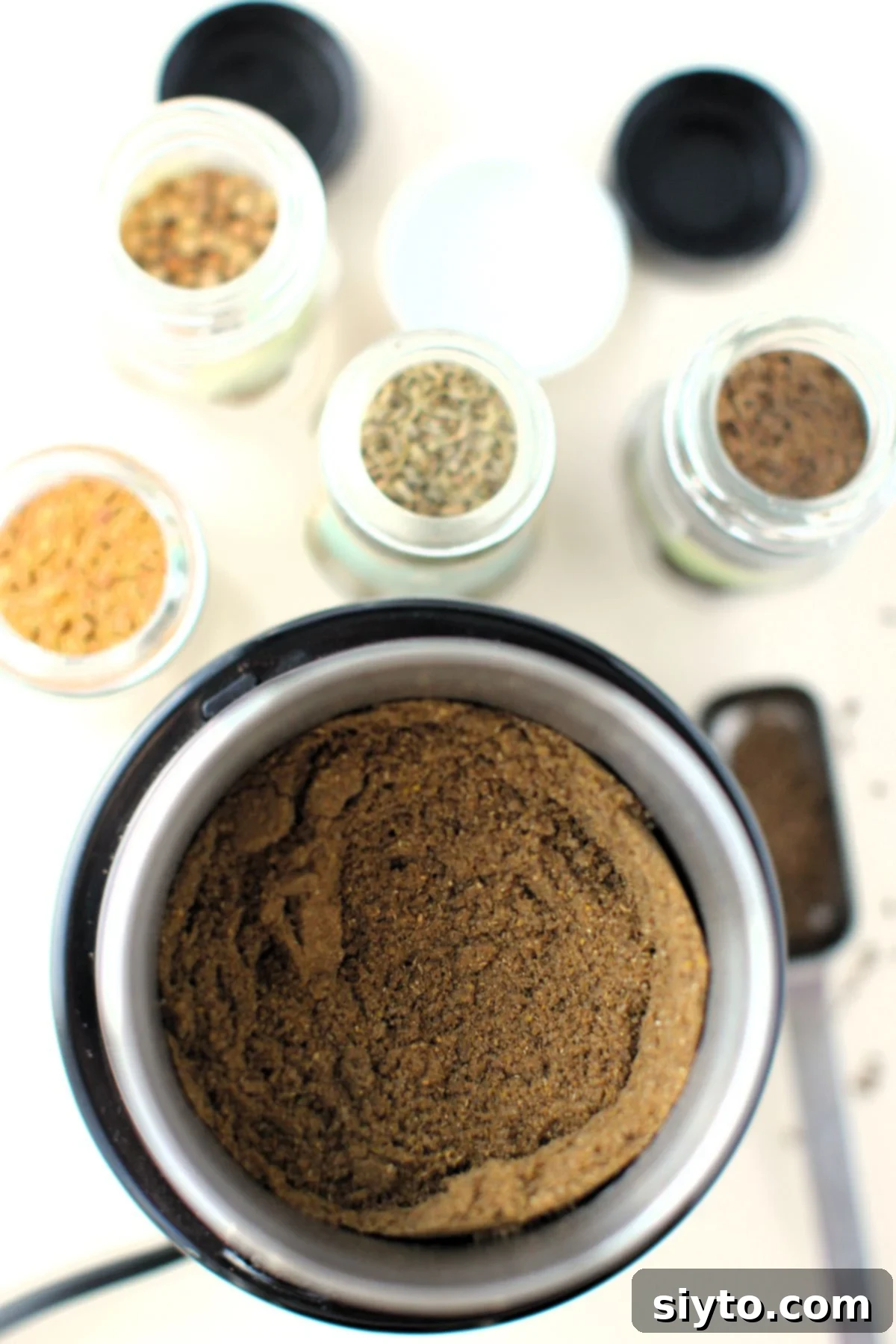 looking down into the spice grinder to see the finished bread spice, with spice jars in background.