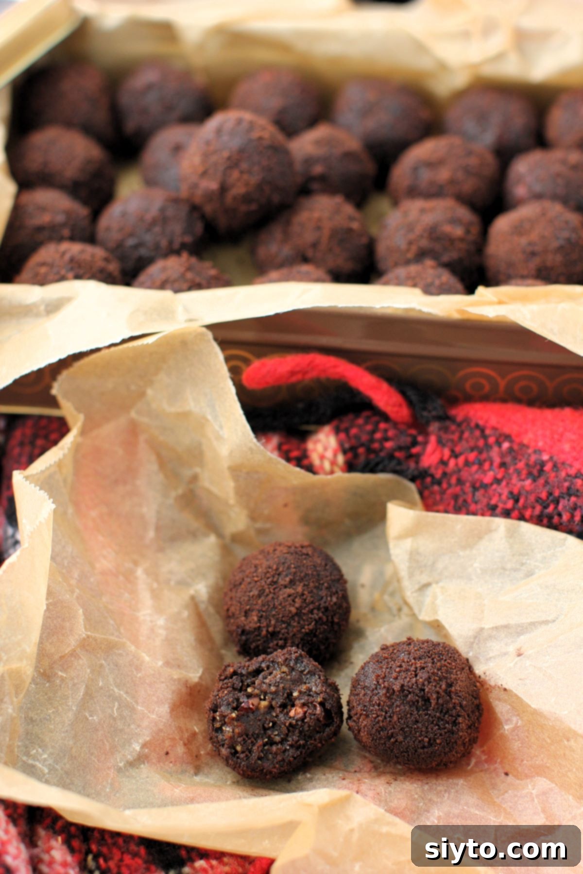 Sweet Bites Snowy Sleds: Lake Louise Adventures 13 Three black licorice balls displayed on a piece of wrinkled brown parchment paper, one of which has a bite taken out of it, with a full tin of licorice balls visible in the background.