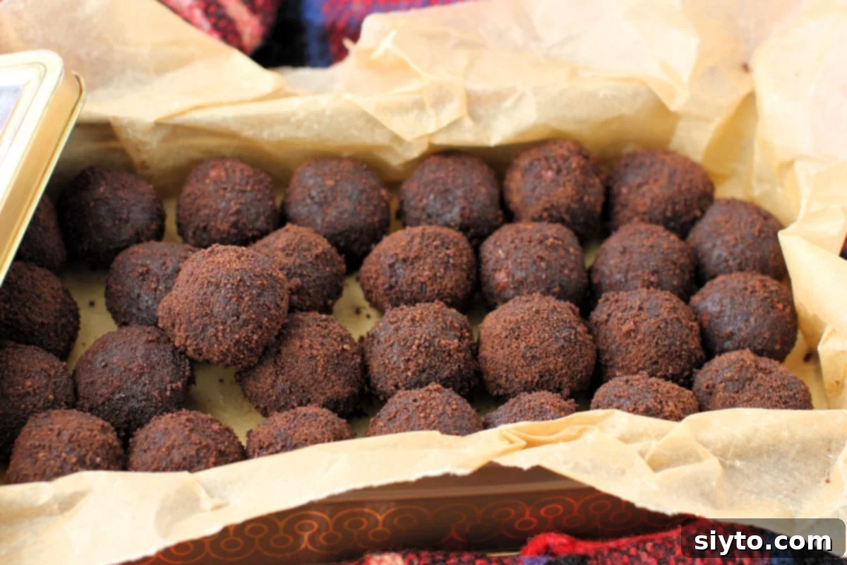 Sweet Bites Snowy Sleds: Lake Louise Adventures 17 An open tin filled with numerous glossy black licorice balls, neatly lined with parchment paper, showcasing the finished healthy snack.