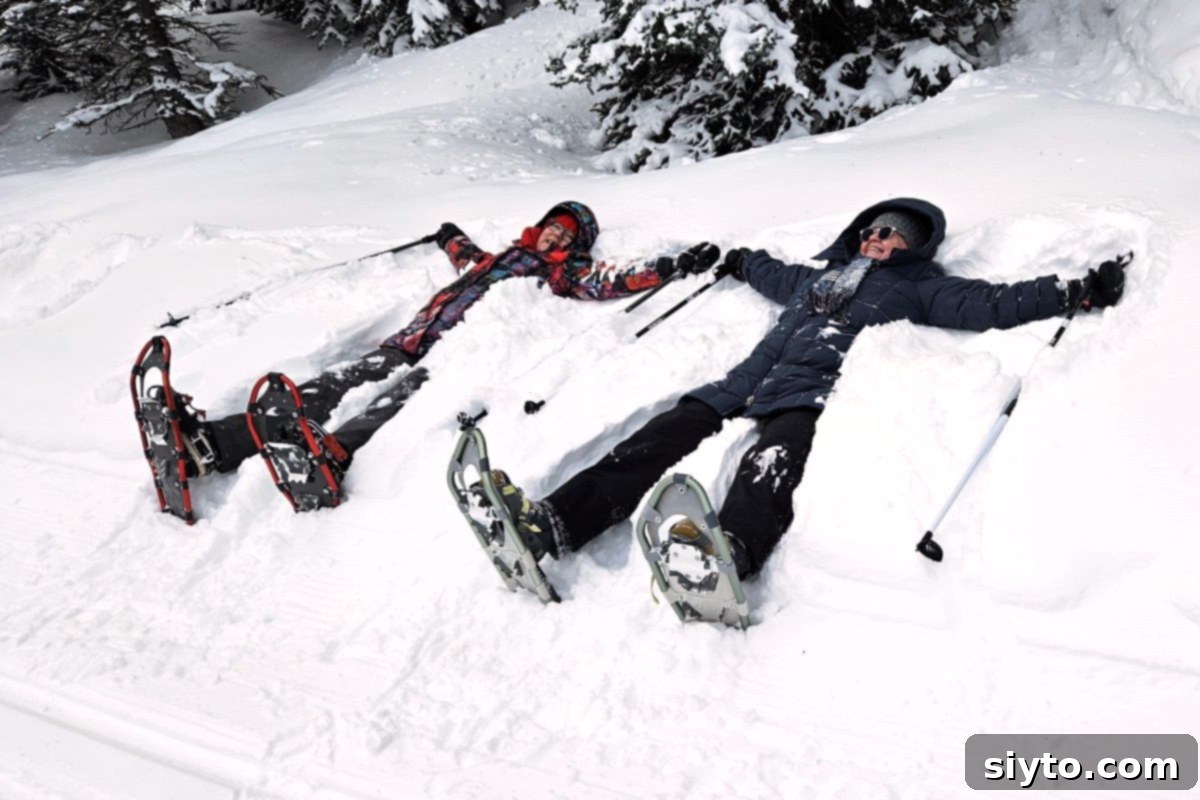 Sweet Bites Snowy Sleds: Lake Louise Adventures 9 Two women with snowshoes strapped to their feet, laughing as they attempt to make snow angels in deep, fresh snow.