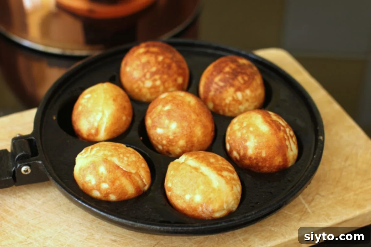 Aebleskiver pan with perfectly golden-brown pancake balls nestled in each indent.