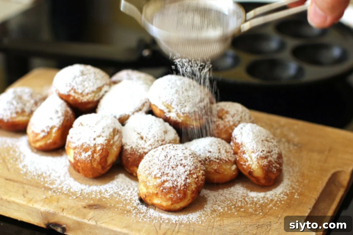Dusting a warm pile of Aebleskiver on a cutting board with a fine layer of icing sugar, preparing them for serving.
