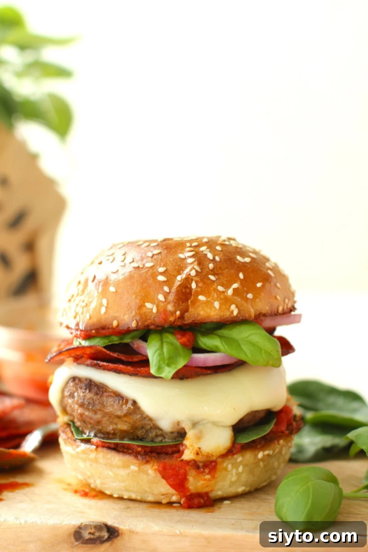 pizza burger with all the fixings on a sesame seed brioche bun.