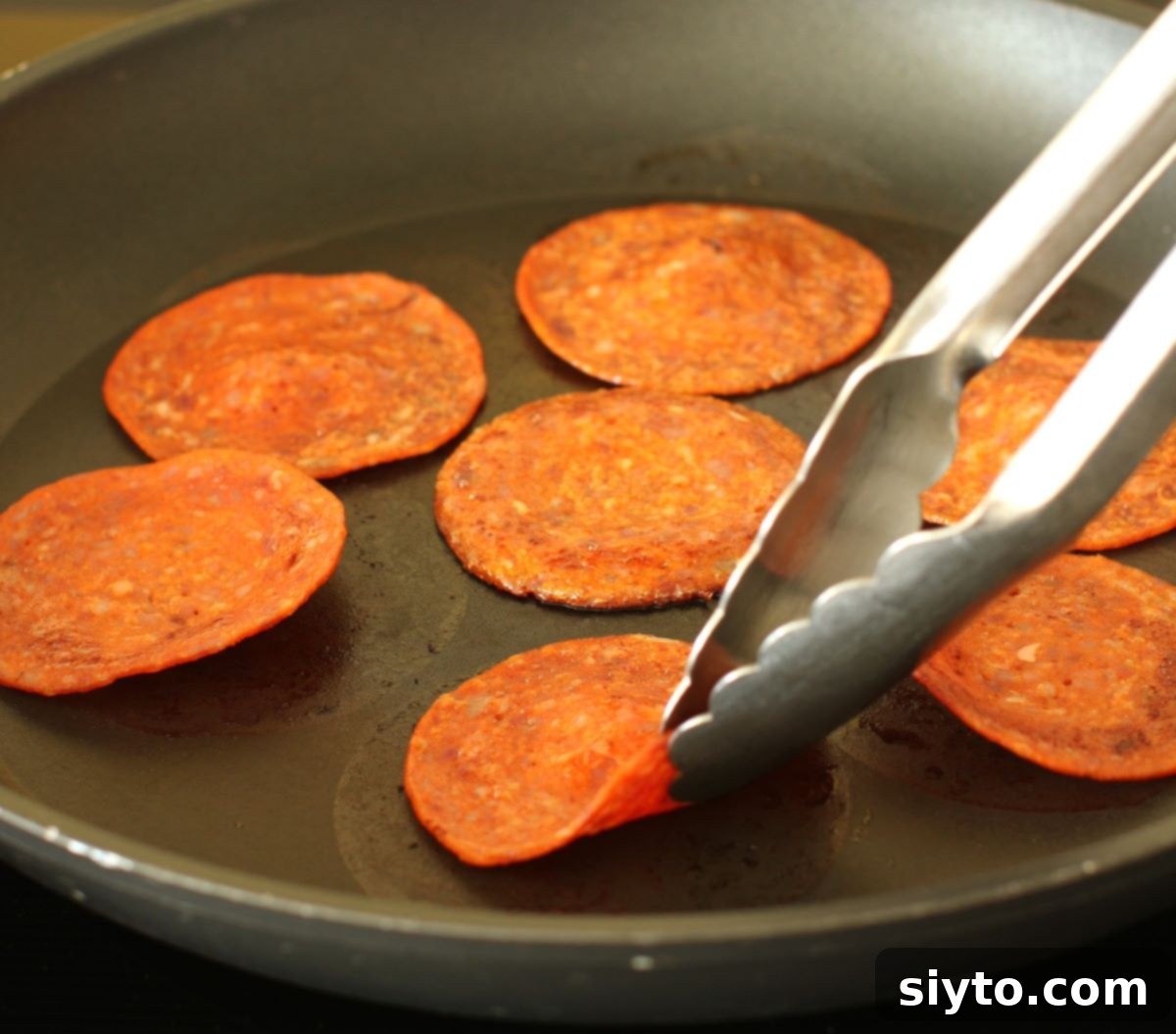 turning the pepperoni slices in the skillet with tongs.