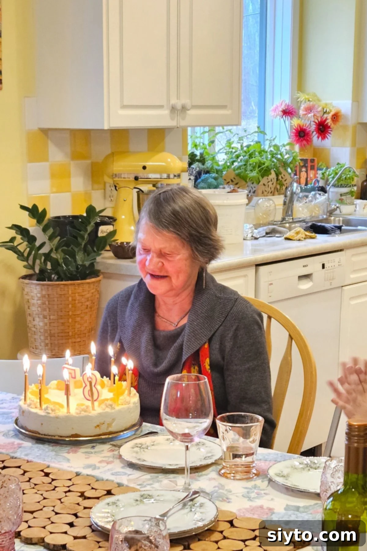 Luscious Mandarin Cream Torte 3 A heartwarming image of a mother, young at heart at 87, ready to blow out the candles on her Mandarinen Sahnetorte. The German Mandarin Cream Torte is beautifully presented, adorned with cream rosettes and mandarin orange segments, making it a perfect birthday cake.