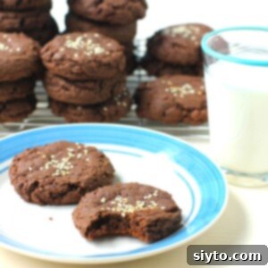 A square photo of soft chocolate tahini cookies on a plate, highlighting their rich color and fudgy texture.
