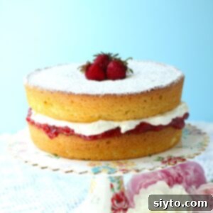 Thumbnail photo of a Gluten Free Victoria Sponge Cake on a cake stand, with strawberries on top.