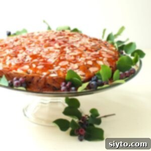 Saskatoon Berry Drizzle Cake 14 The Saskatoon Drizzle Cake, beautifully glazed and adorned with fresh saskatoon berries, sitting on a glass cake stand, ready to be enjoyed.