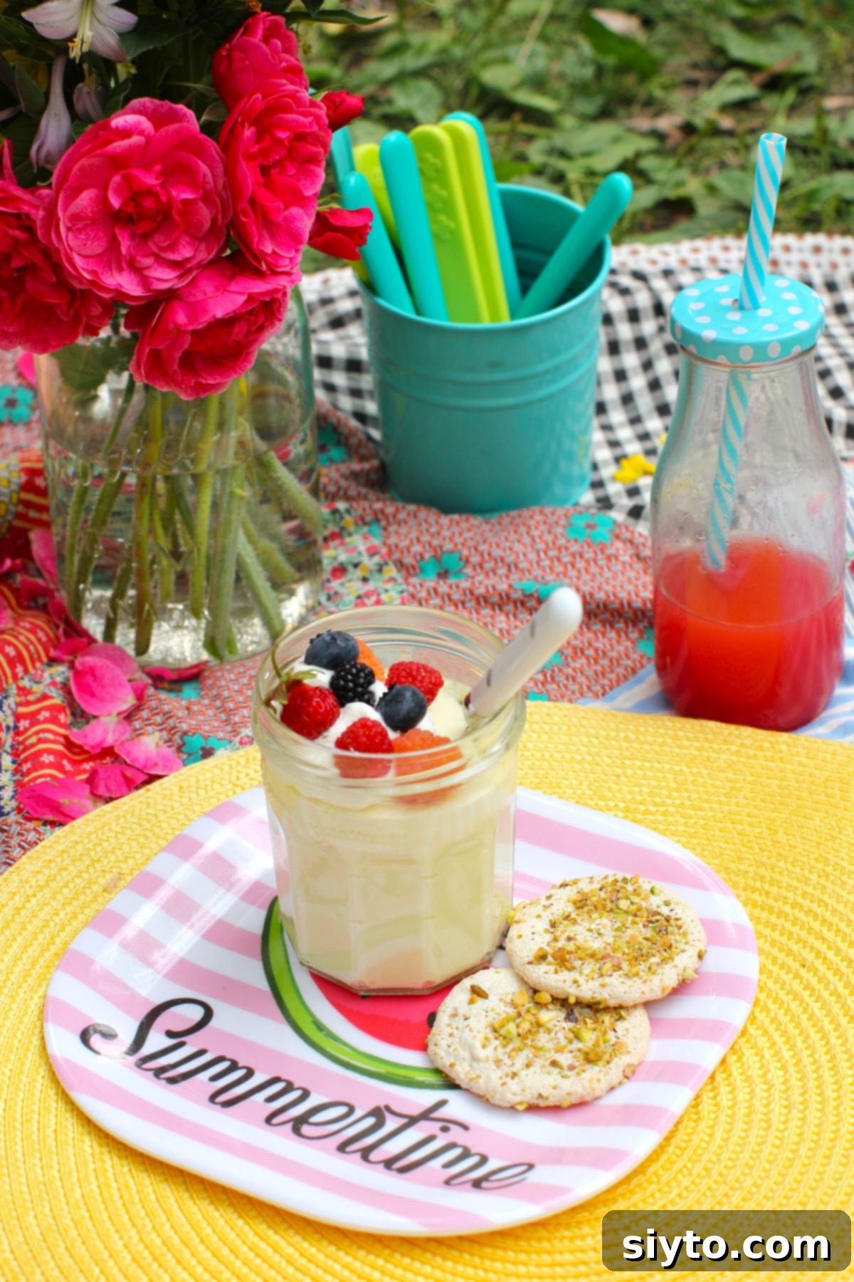 A single jar of luscious lemon mousse, adorned with fresh mixed berries and a dollop of whipped cream, presented on a summer-themed plate atop a yellow placemat, with two crunchy nut meringue cookies nearby.